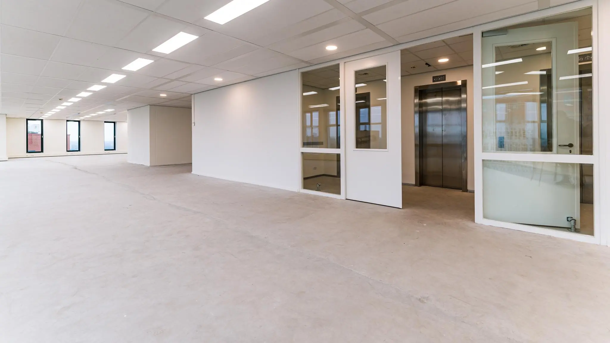 Leeg kantoorpand aan de George Hintzenweg met zicht op een lift en glazen tussenwand.